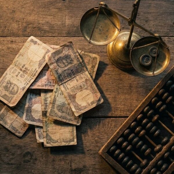 Flat-lay showing rupee notes, a brass scale, and an abacus, illustrating the 'margin of safety' in Indian investing.