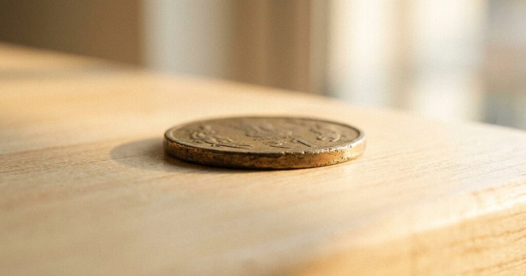 Close-up of an aged Indian rupee coin on pale wood, symbolizing first principles thinking in business and investing.