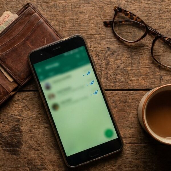 A wooden table with a WhatsApp message, chai, and wallet, illustrating sales conversations transitioning to WhatsApp.