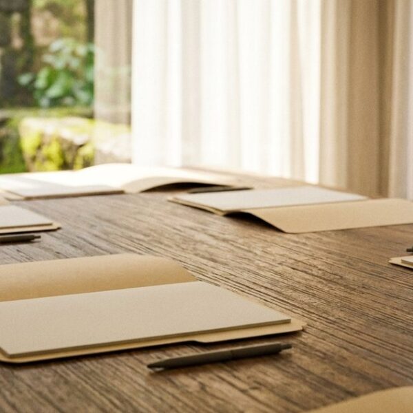 A wooden conference table with open folders and pens, symbolizing structured business meetings in an Indian context.