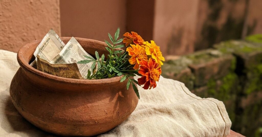 Close-up of a clay pot with currency and marigold, symbolizing negotiation and ethical influence in sales.