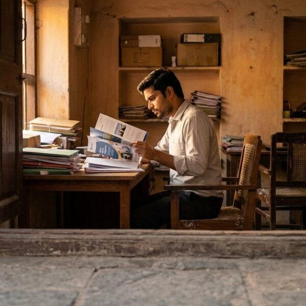 A young person examines company brochures in an Indian business, embodying a focused job search approach.