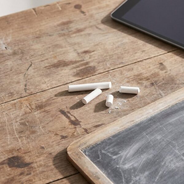Chalk and a blackboard beside a tablet, illustrating the tension between traditional and AI-driven education methods.