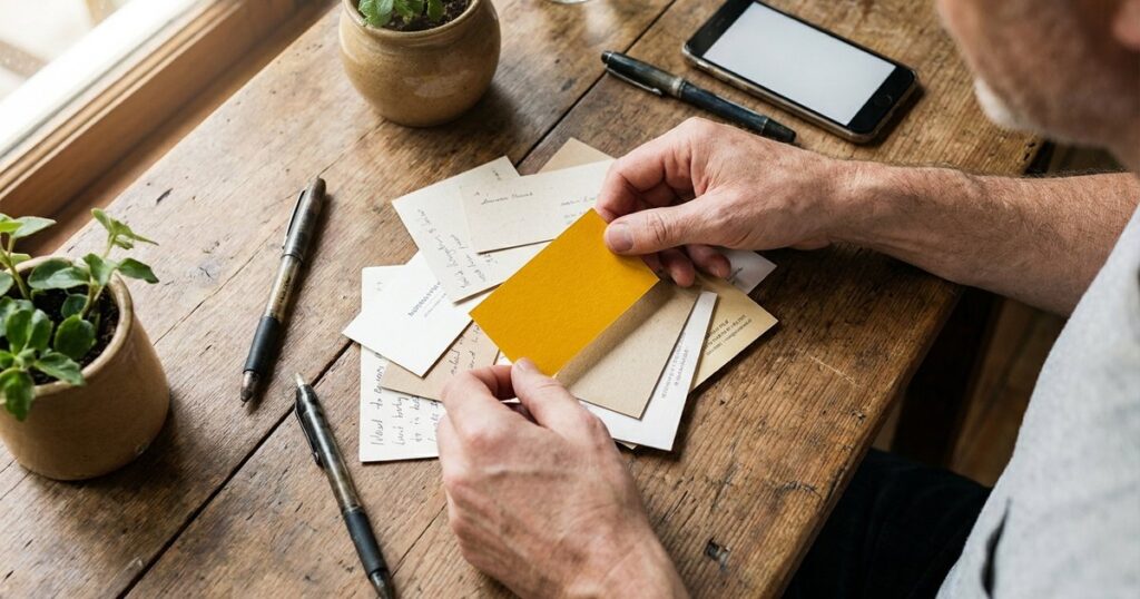 Hands sorting business cards and notes, illustrating the challenge of finding angel investors in India without introductions.