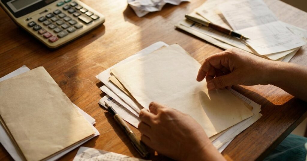 Indian investor sorts investments and tax papers on a warm wooden table.