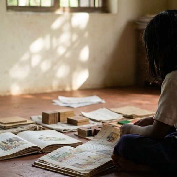 A thoughtful student surrounded by educational materials, reflecting on the schooling system's effectiveness in an Indian classroom.