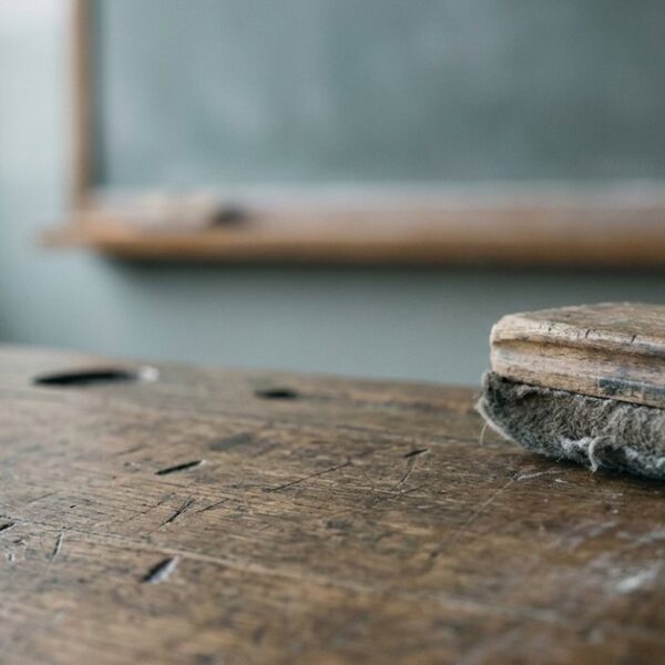 Close-up of a chalk duster on a wooden desk, symbolizing traditional teacher-centered education methods.