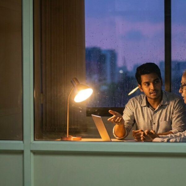 Two people discussing AI startups in India seen through a doorway, reflecting the article's focus on angel investors.